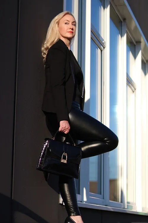 Melanie Gobbo mit Handtasche an einer Glasfassade
