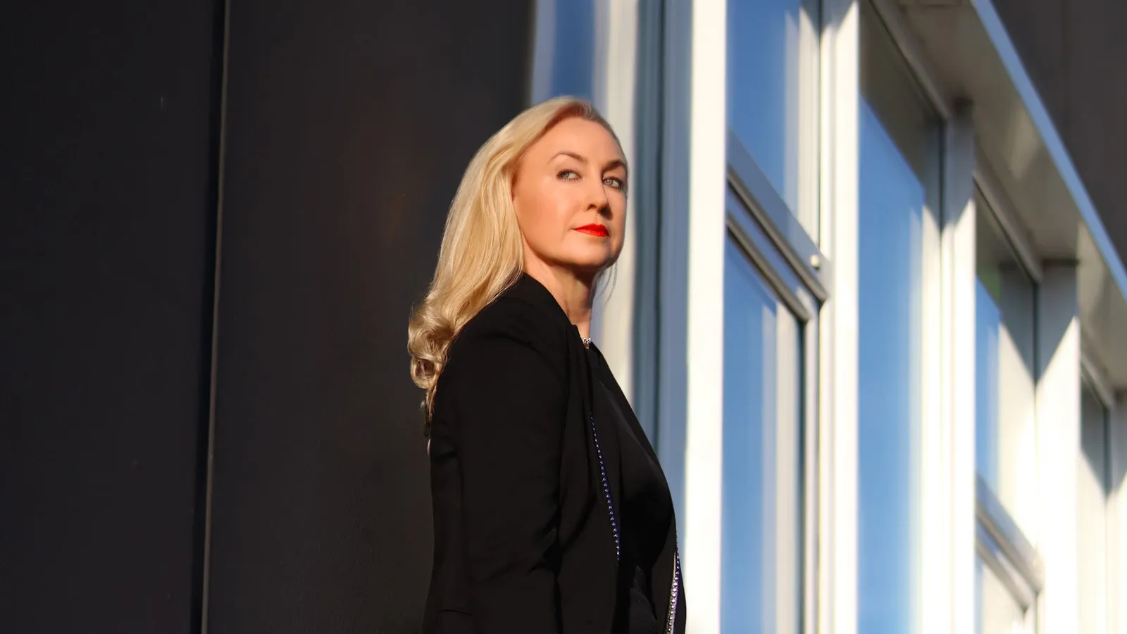 Melanie Gobbo in schwarzem Blazer vor einer Glasfassade